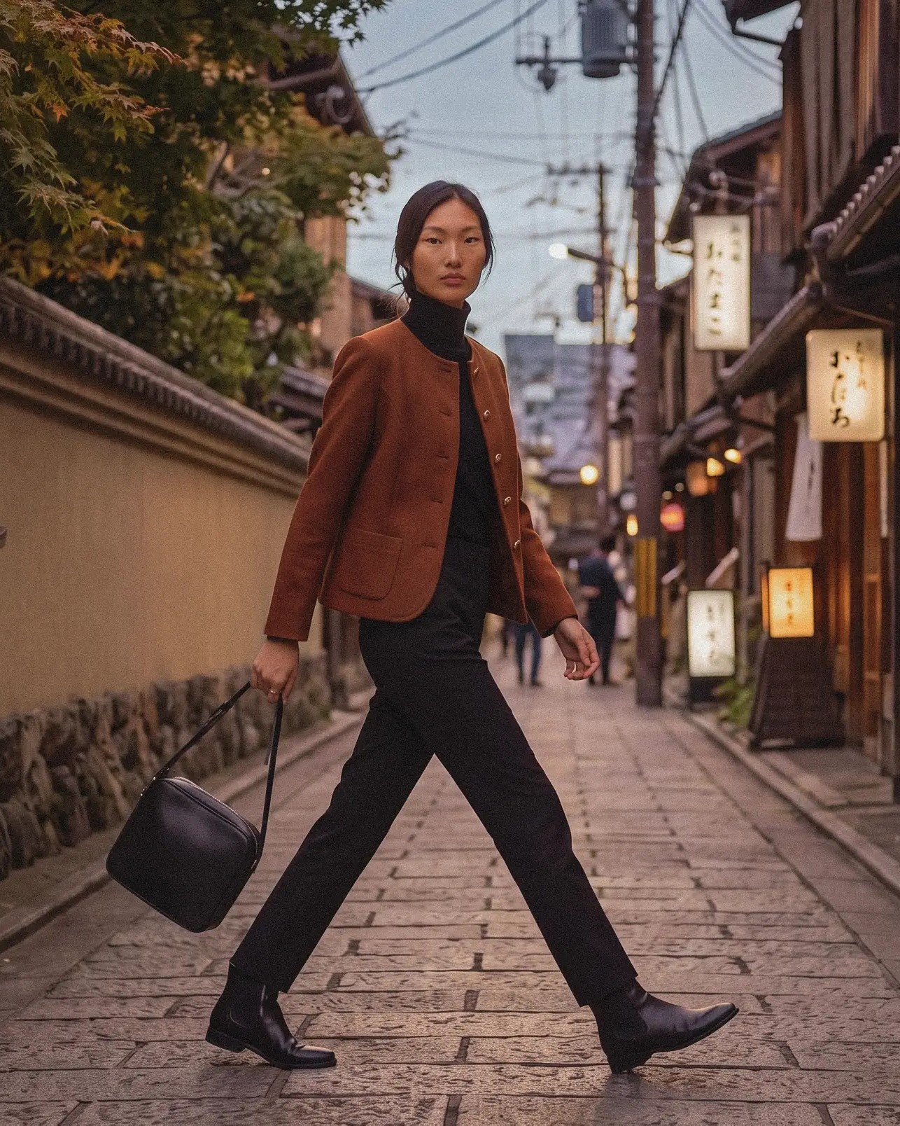 Evening outfit: the older wool jacket worn open over a black turtleneck and black trousers, walking down a lantern-lit street at dusk